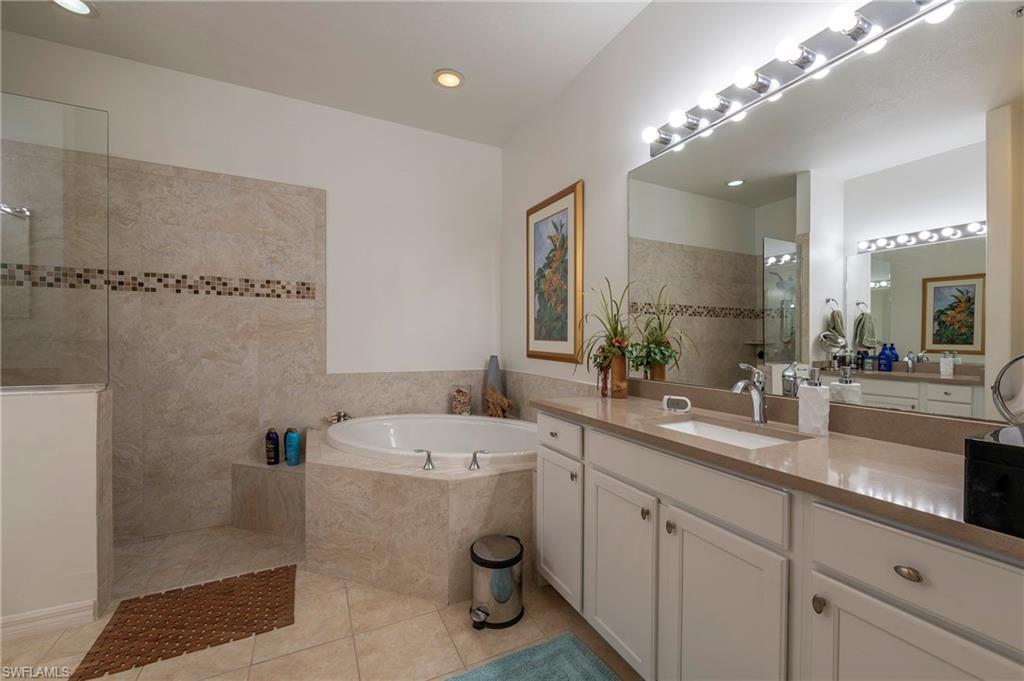 4675 Winged Foot Court, Unit 102 Naples, FL 34114 - Photo 10 of 31 a bathroom with a double vanity sink a large mirror and shower