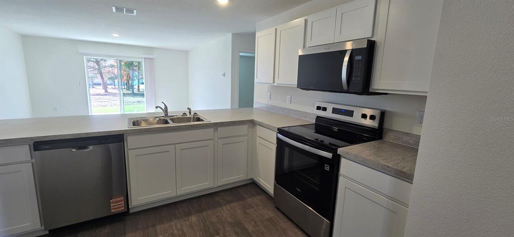 6010 Southwest 128th St Road Ocala, FL 34473 - Photo 10 of 16 a kitchen with stainless steel appliances granite countertop a sink stove and microwave