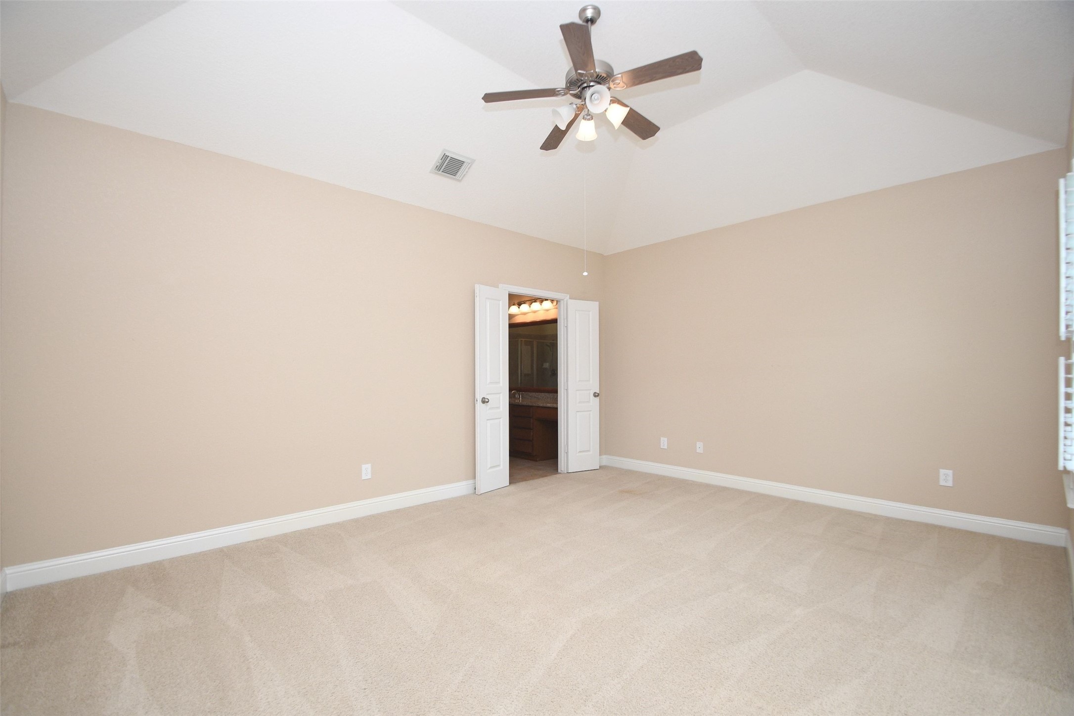 5803 Oakdale Meadows Spring, TX 77379 - Photo 19 of 21 This spacious bedroom features neutral walls, plush carpeting, and a vaulted ceiling with a ceiling fan. It includes double doors leading to an en-suite bathroom, creating a comfortable and inviting space.
