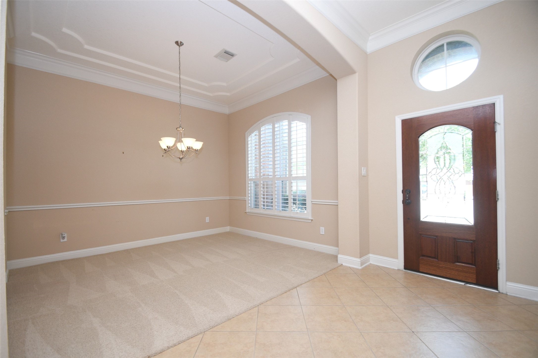 5803 Oakdale Meadows Spring, TX 77379 - Photo 2 of 21 This inviting entryway features high ceilings, a stylish chandelier, and a mix of tile and carpet flooring. The large arched window provides natural light, and the elegant wooden door adds a touch of sophistication.