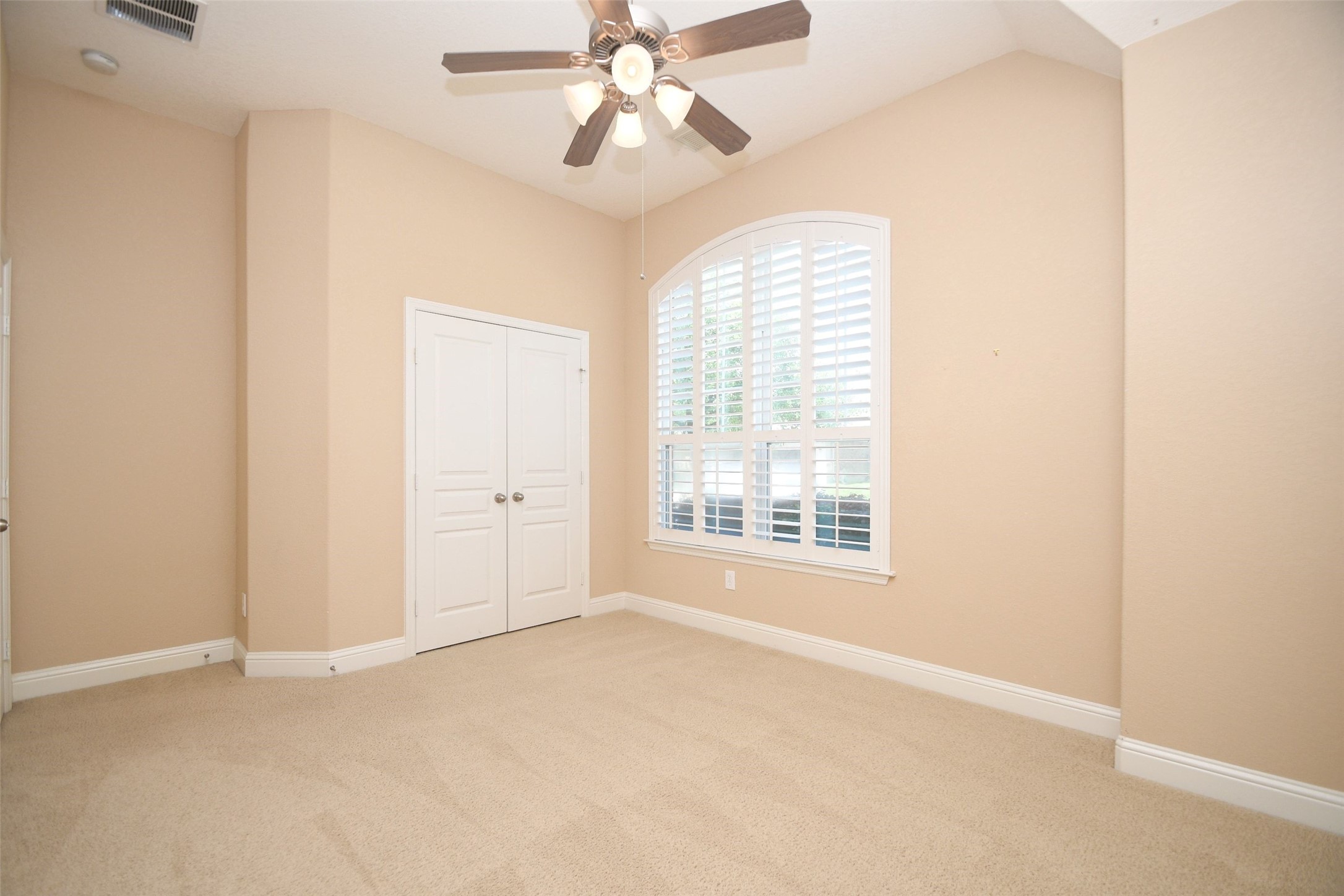 5803 Oakdale Meadows Spring, TX 77379 - Photo 5 of 21 This room features neutral walls and carpet, a ceiling fan with lights, large arched window with shutters, and a double-door closet, offering a bright and spacious feel.