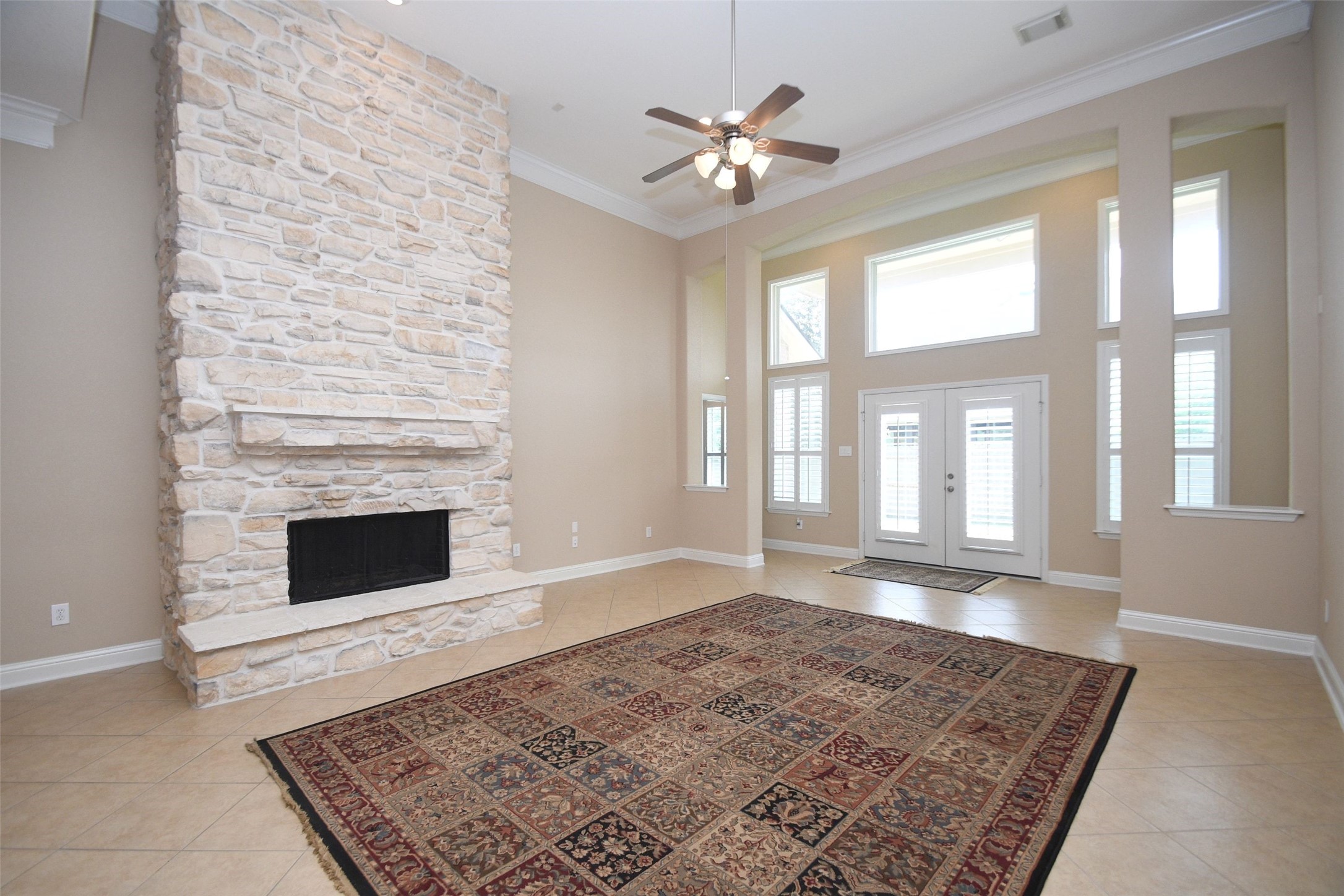 5803 Oakdale Meadows Spring, TX 77379 - Photo 8 of 21 This spacious living room features a striking stone fireplace, high ceilings with a ceiling fan, and abundant natural light from large windows and French doors. The neutral tile flooring and floor to ceiling stone fireplace.
