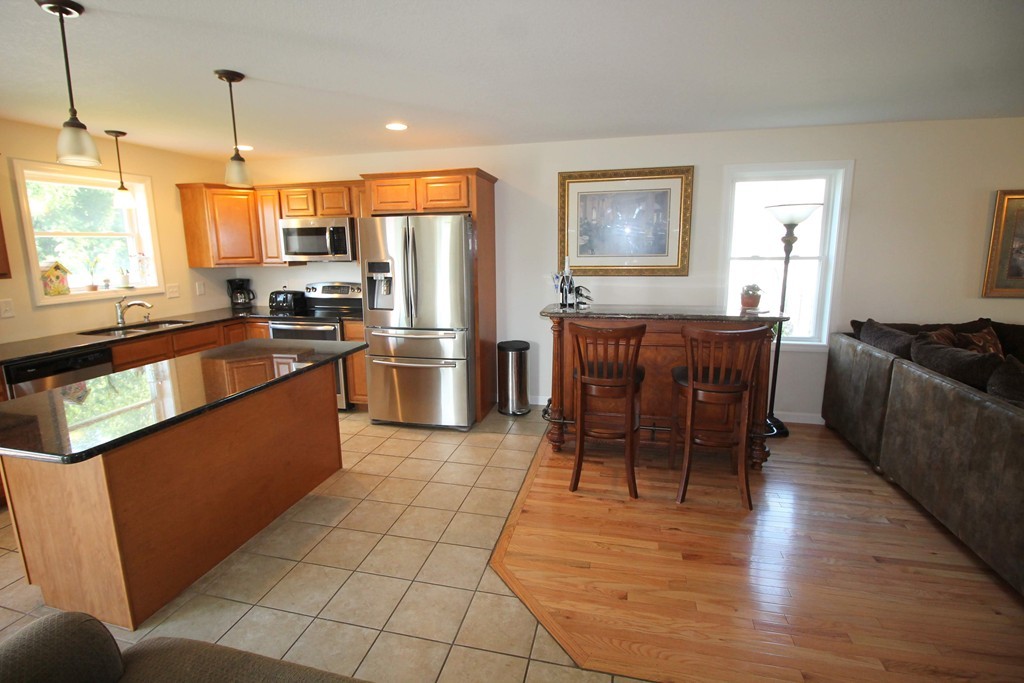 264 Island Pond Road Springfield, MA 01118 - Photo 4 of 13 a kitchen with stainless steel appliances granite countertop a refrigerator a stove a sink a dining table and chairs with wooden floor