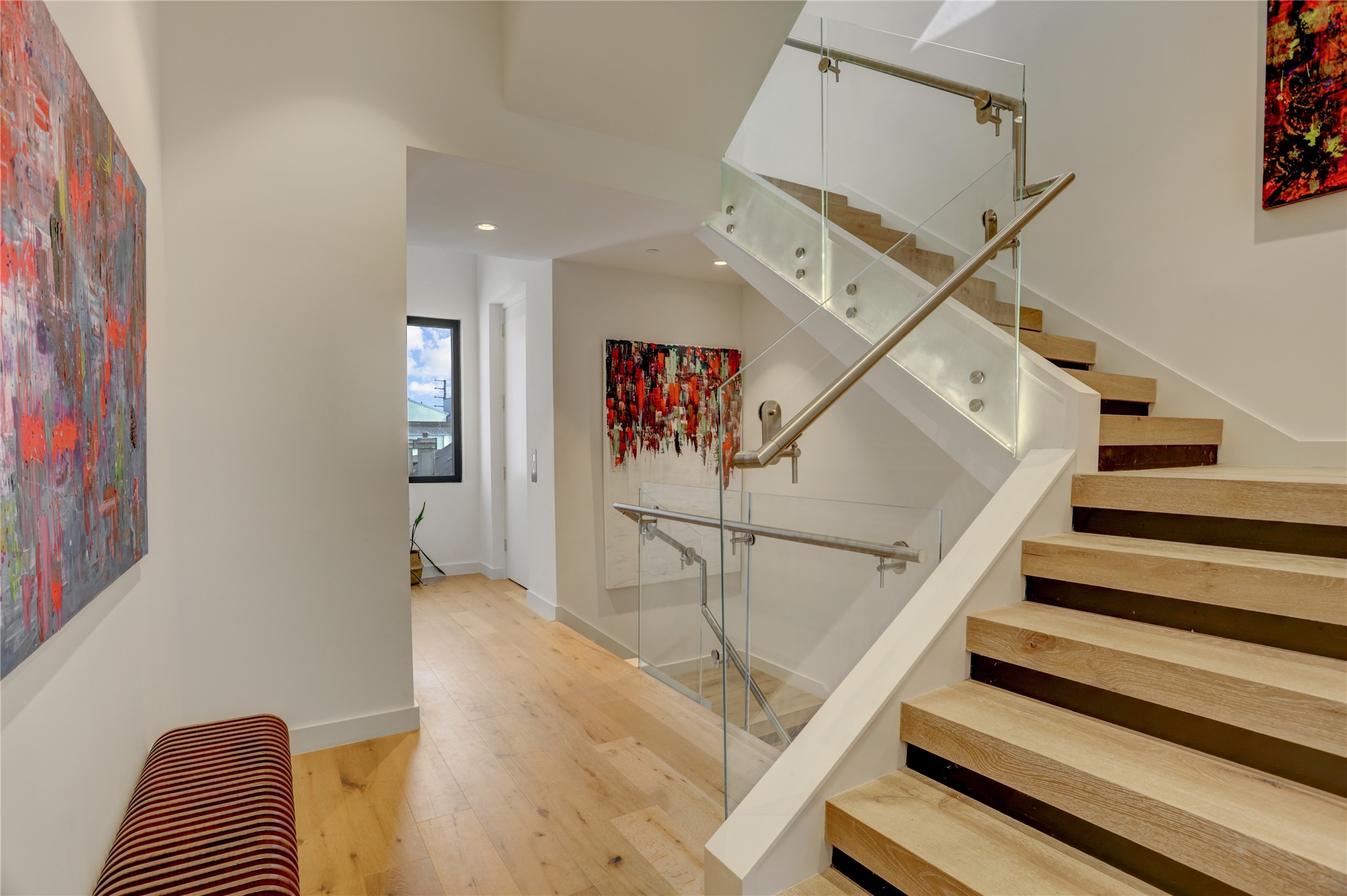 1807 Indiana Street Houston, TX 77006 - Photo 20 of 35 Third-Floor Landing: Spacious gallery hallway showcasing modern open-riser stairs, custom glass railings, wide-plank flooring, and direct access to the private elevator entrance.