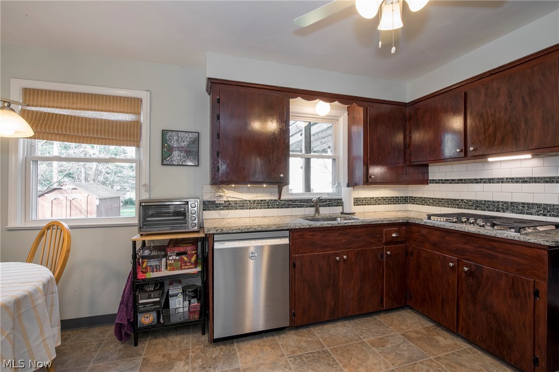 1170 Roland Road Lyndhurst, OH 44124 - Photo 9 of 36 Kitchen with sink, light tile floors, backsplash, stainless steel appliances, and ceiling fan