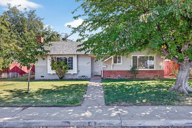 a front view of a house with a garden and trees