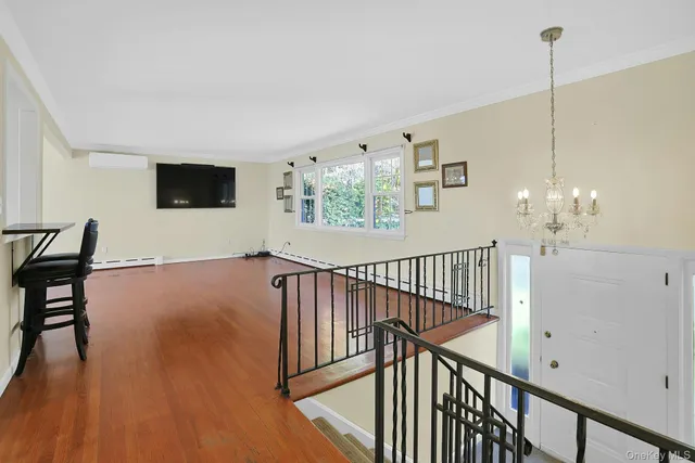 a view of a livingroom with furniture stairs wooden floor and windows