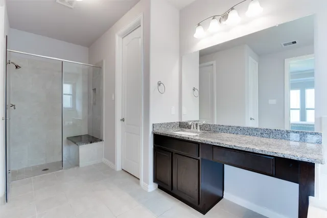 a bathroom with a granite countertop double vanity sink and mirror