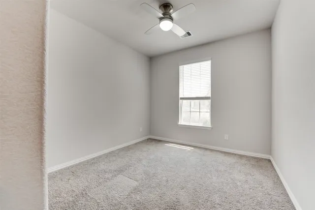 an empty room with a window and a fan