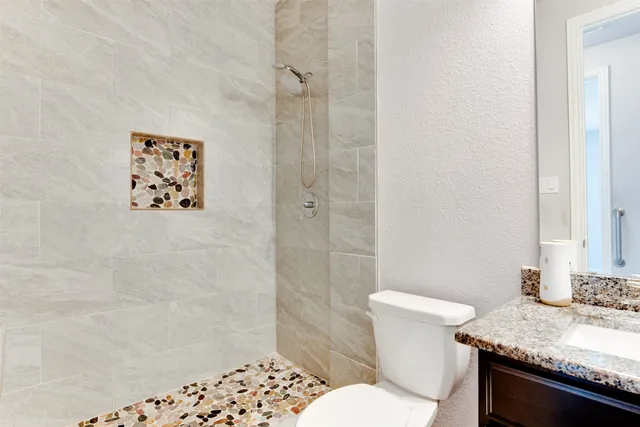 a bathroom with a granite countertop sink a toilet and shower