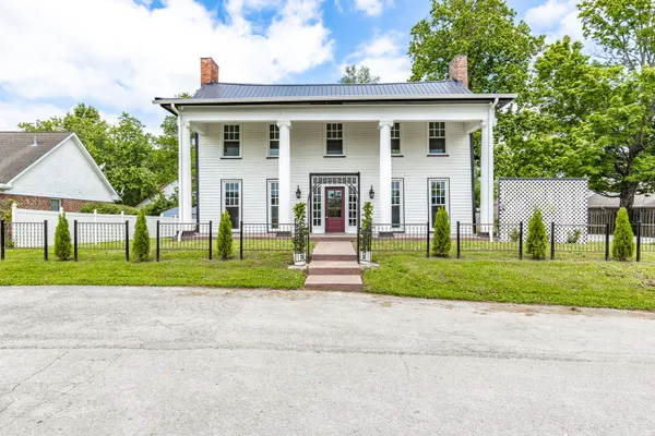 a front view of a house with a yard and trees