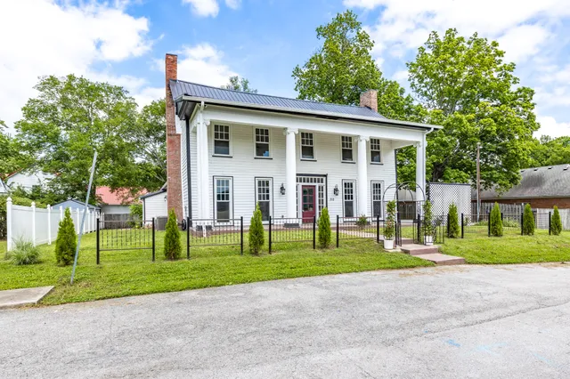 a view of a house with a yard and large trees