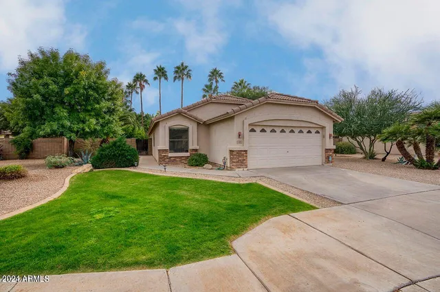 a view of a white house with a yard plants and a table and chairs