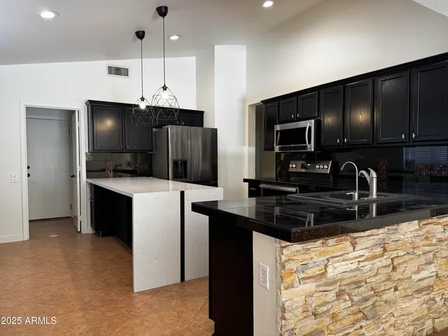 a kitchen with stainless steel appliances a refrigerator a stove a sink a counter space and cabinets