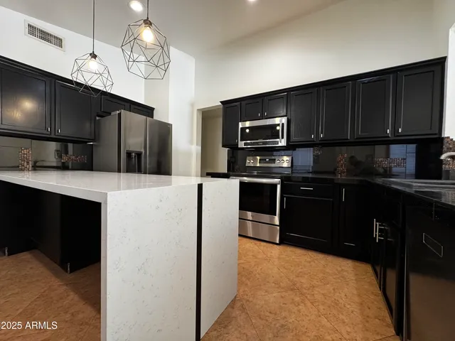 a kitchen with kitchen island granite countertop stainless steel appliances and wooden cabinets