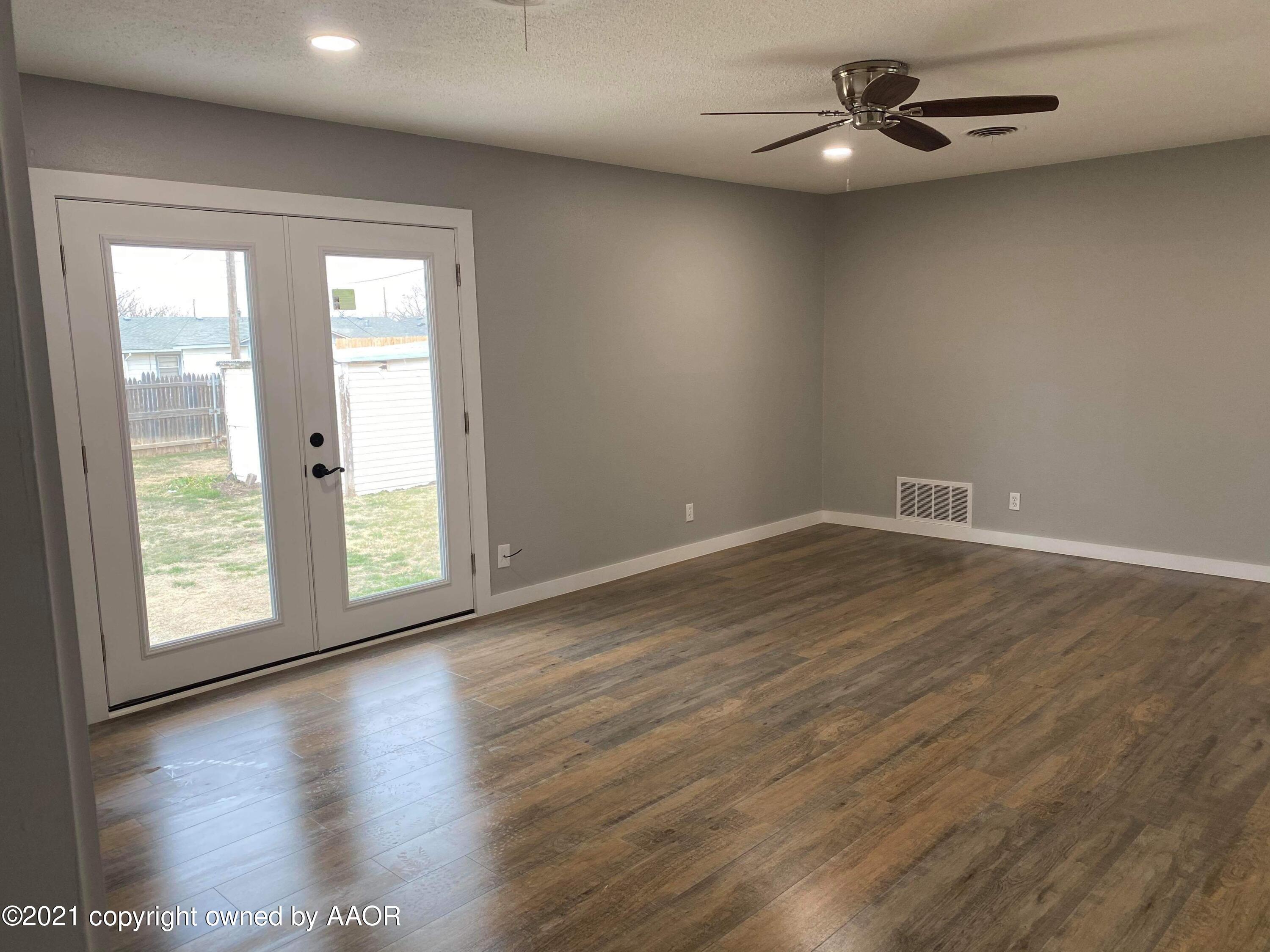 4304 South Bonham Street Amarillo, TX 79110 - Photo 6 of 9 an empty room with wooden floor chandelier fan and windows