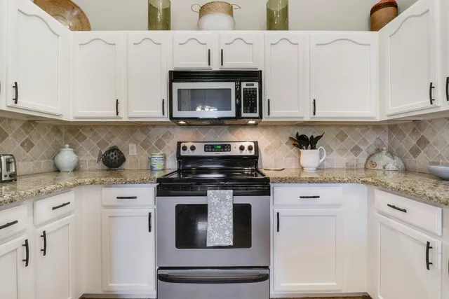 a kitchen with granite countertop white cabinets and stainless steel appliances