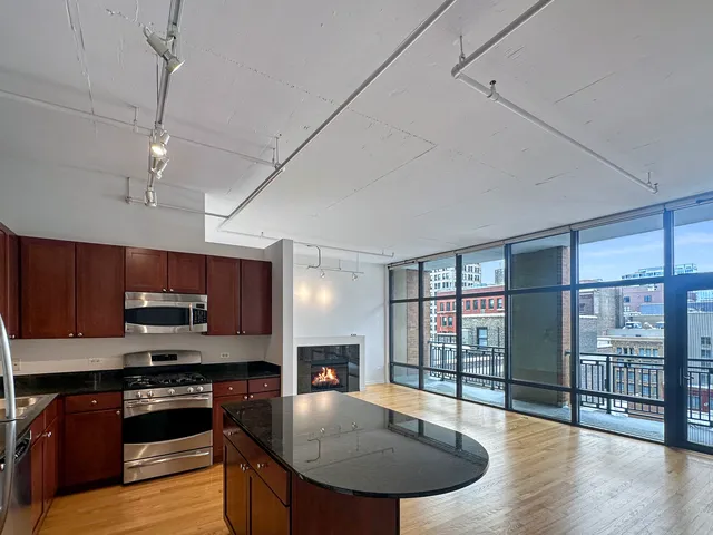 a kitchen with stainless steel appliances granite countertop a stove top oven a sink dishwasher a dining table and chairs with wooden floor