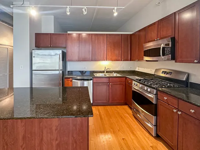 a kitchen with stainless steel appliances granite countertop wooden cabinets a stove top oven a sink and dishwasher