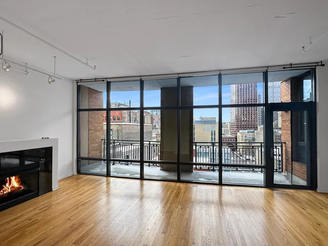 a view of an empty room with wooden floor and a fireplace