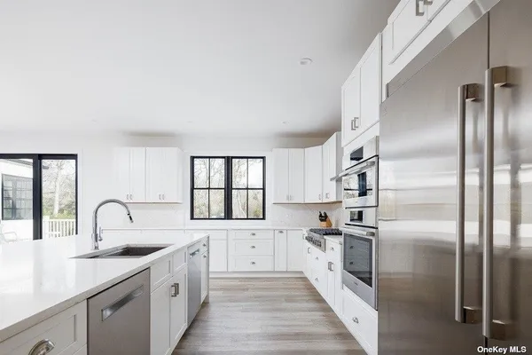 a kitchen with stainless steel appliances a refrigerator sink and white cabinets