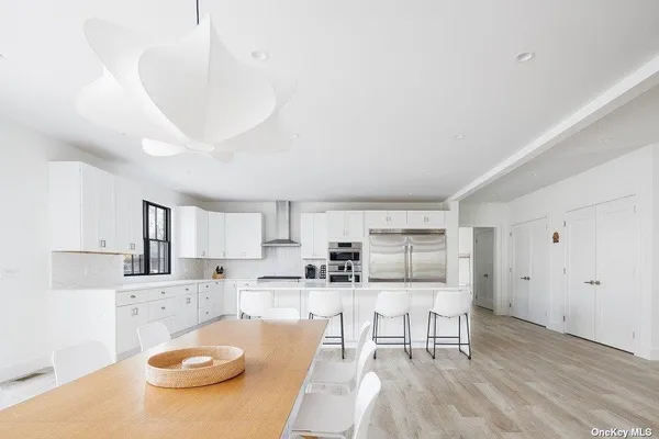 a kitchen with stainless steel appliances a refrigerator a sink a stove and white cabinets