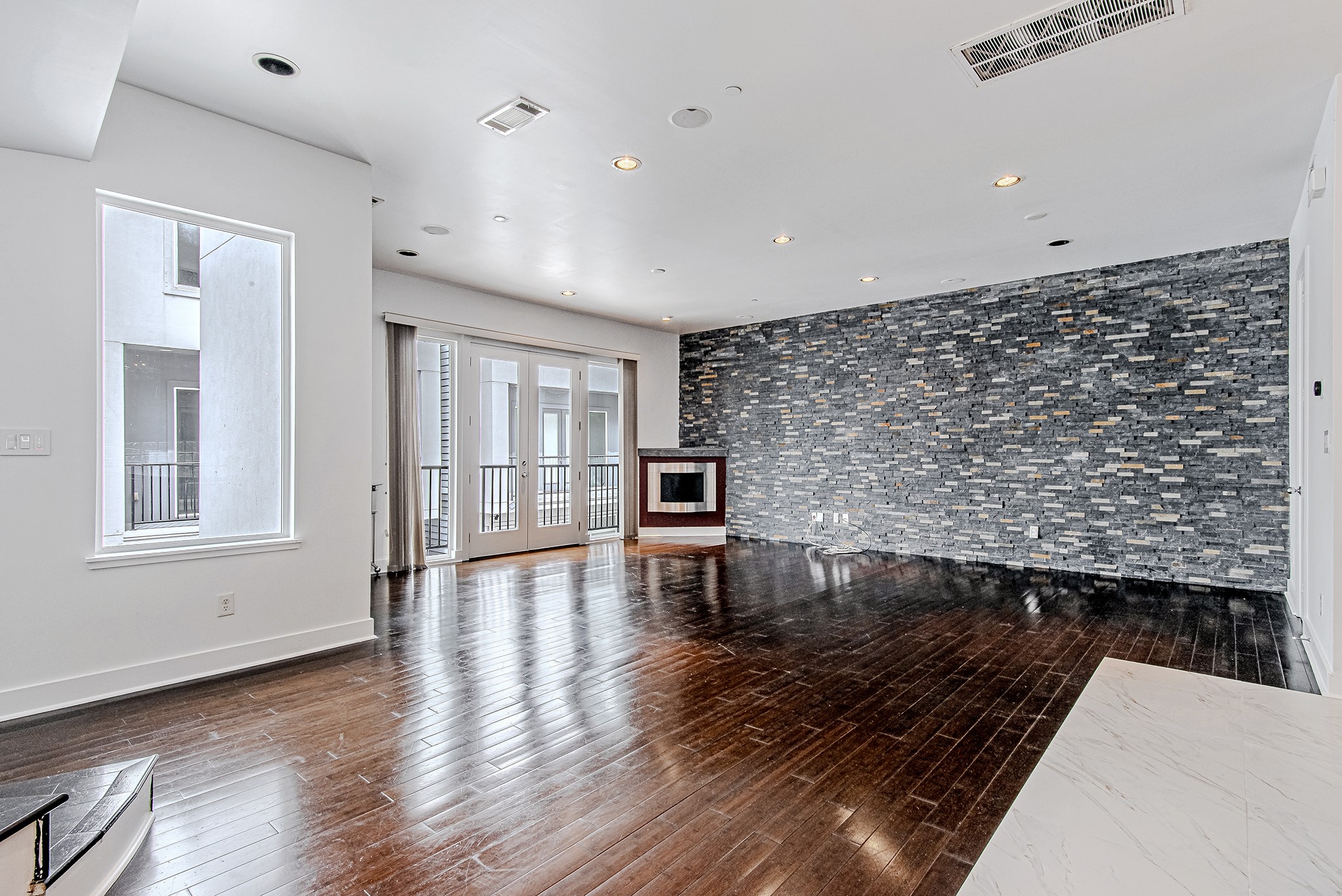 2025 Colquitt Street, Unit E Houston, TX 77098 - Photo 13 of 29 Living area with statement accent wall and wide-plank flooring.