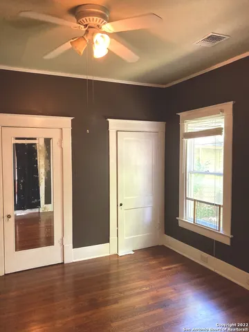 an empty room with wooden floor cabinet and windows