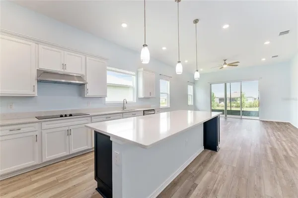 a large kitchen with kitchen island a sink a center island stainless steel appliances and a window