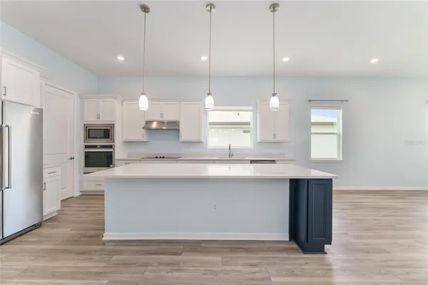 a large kitchen with a sink a counter top stainless steel appliances and cabinets