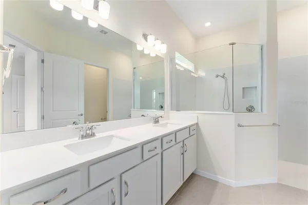 a spacious bathroom with a double vanity sink mirror and shower