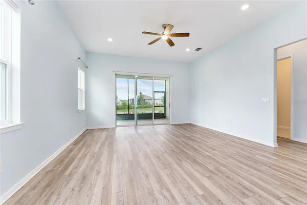 a view of empty room with wooden floor and fan