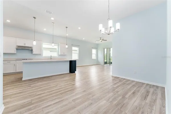a large kitchen with kitchen island a stove a sink a center island and wooden floor
