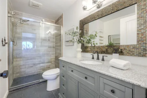 a bathroom with a granite countertop sink a toilet and shower