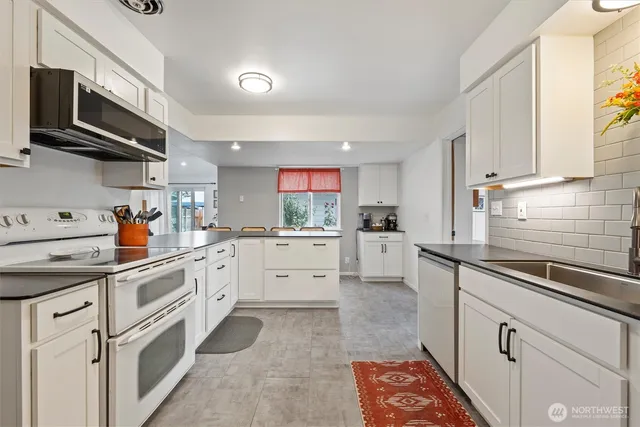 a kitchen with white cabinets appliances and a window