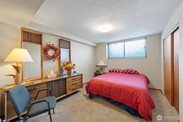 a bedroom with a bed and a lamp on dresser