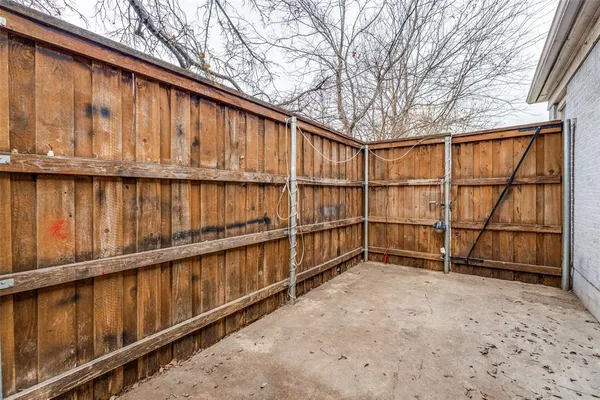 a view of backyard with large trees and a wooden fence