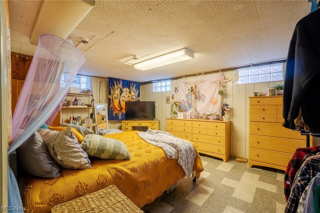15022 Triskett Road Cleveland, OH 44111 - Photo 27 of 35 Carpeted bedroom featuring multiple windows and wood walls