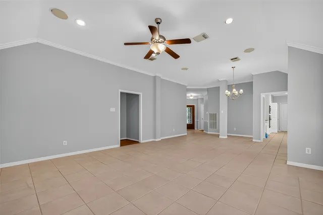 an empty room with ceiling fan and windows