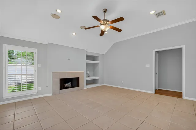 a view of an empty room with chandelier fan and fire place