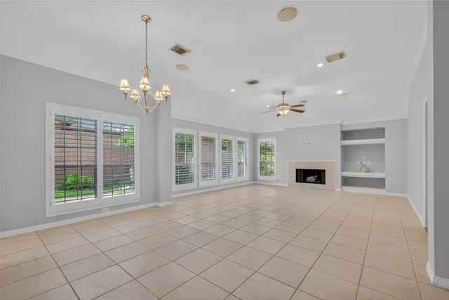 a view of an empty room with chandelier and fireplace
