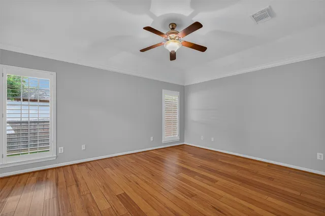 a view of empty room with wooden floor and fan