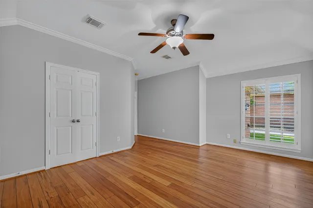 a view of an empty room with wooden floor and a window