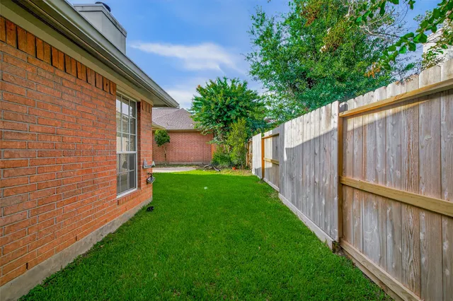 a backyard of a house with plants and large tree