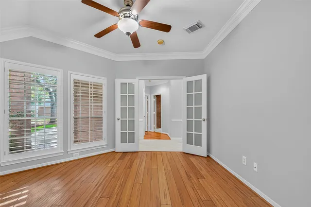 an empty room with wooden floor and windows