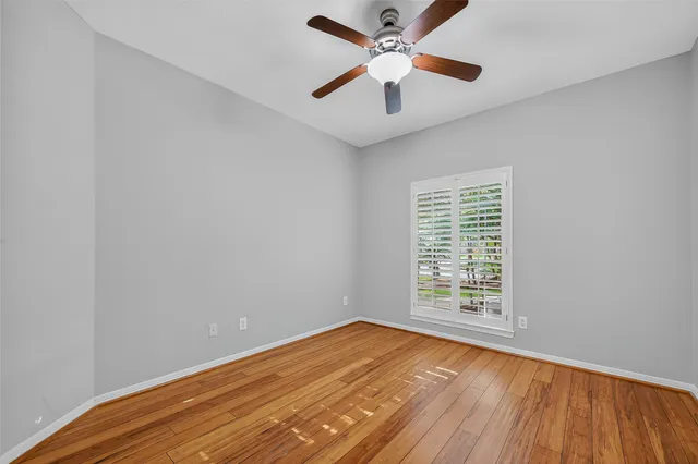 an empty room with wooden floor fan and windows