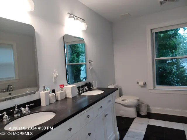a bathroom with a double vanity sink toilet and a mirror