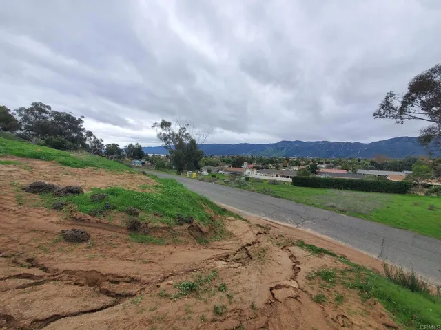 a view of a road with big yard and large trees