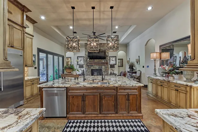 a kitchen with kitchen island granite countertop a sink a counter top space cabinets and stainless steel appliances