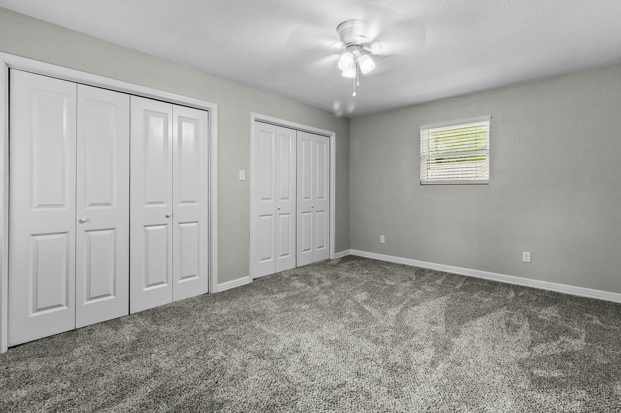 21 Red Oak Circle Point Blank, TX 77364 - Photo 16 of 32 This room features neutral walls and carpeting, dual closets with white doors, a ceiling fan with lights, and a window for natural light, offering a clean and spacious feel.